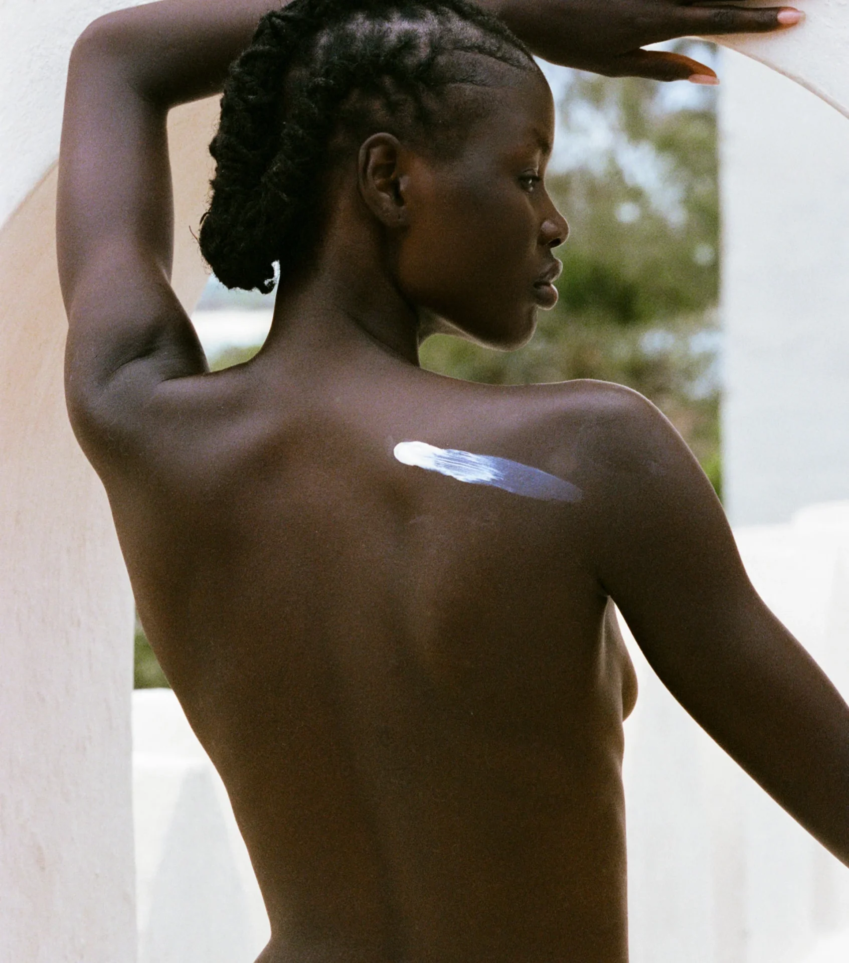 Modell som påfører solkrem på skulderen i naturlig lys