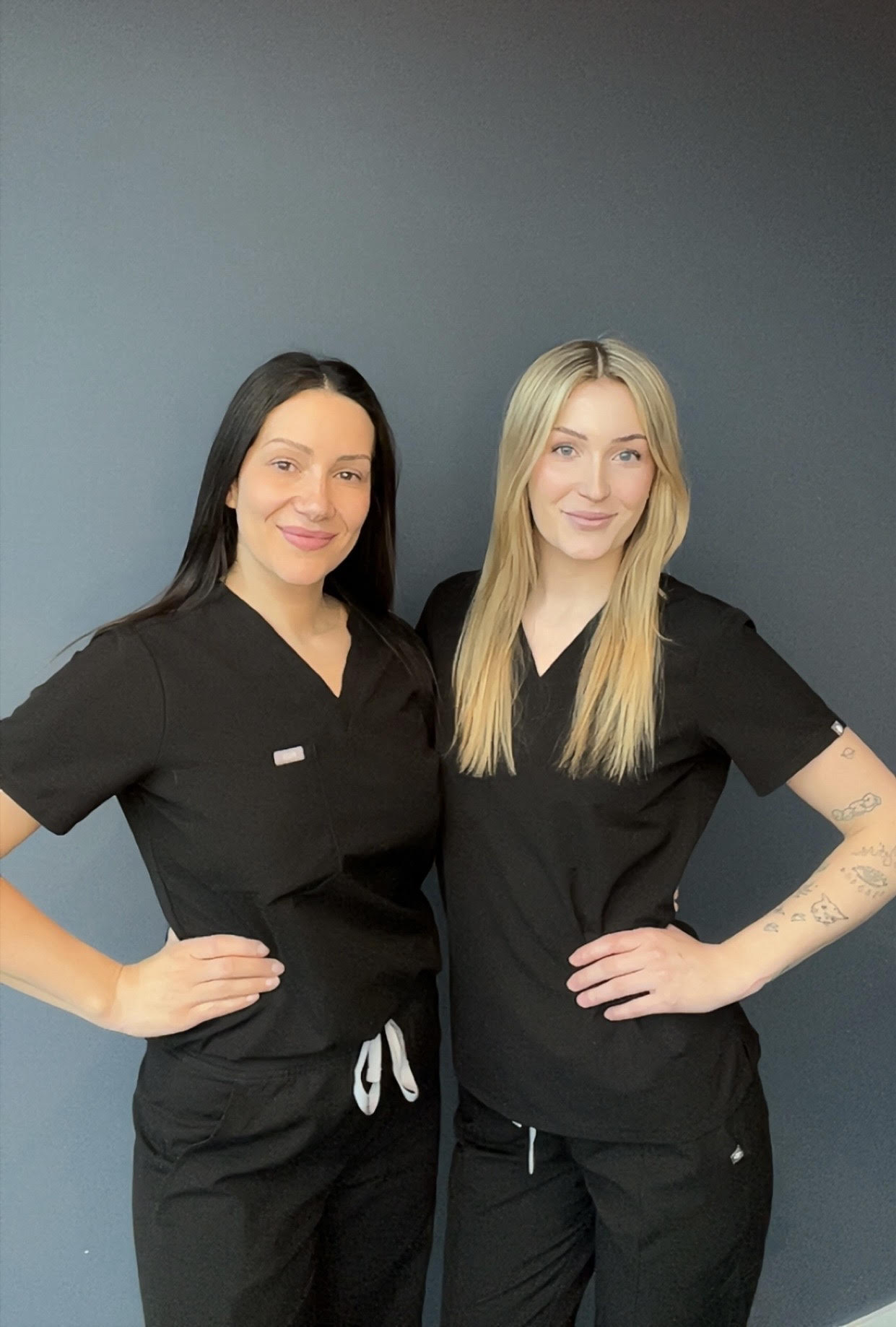 To hudterapeuter hos Eliteklinikken smiler og står side og side, klare for å utføre populære hudbehandlinger